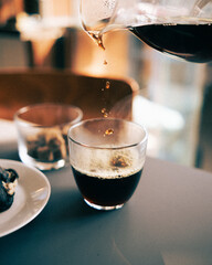 Pouring black coffee into a glass.