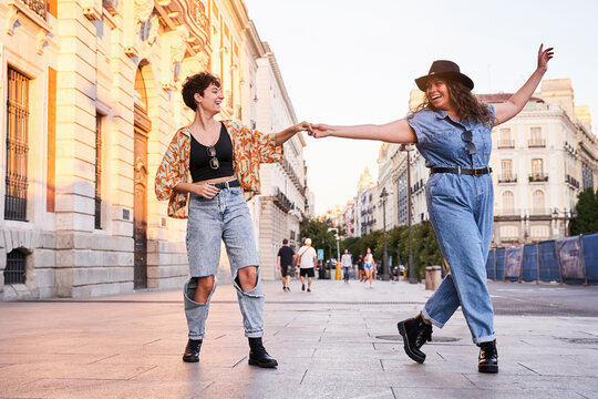 Merry girlfriends dancing on street