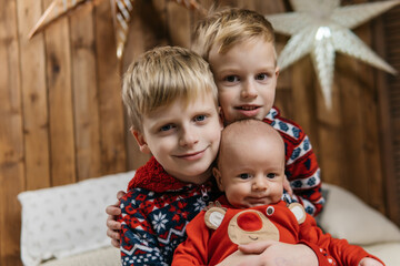 three brothers in christmas pajamas, christmas background with golden stars and glowing garlands. High quality photo