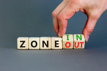 Zone in or out symbol. Concept words Zone in and Zone out on wooden cubes. Beautiful grey table grey background. Businessman hand. Business zone in or out concept. Copy space.