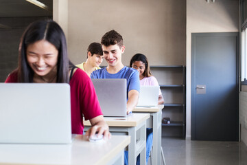 Large Group of Multi Ethnic smiling Students Working on the Laptops while Listening to Lecture in the Classroom. Young cheerful People Study University. Selective focus in the guy. High quality photo