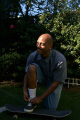 Portrait of young man tying shoe in backyard on skateboard

