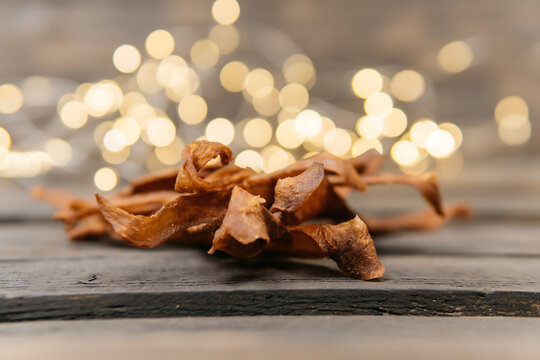 Chewy and delicious chiken jerky, dried meat cut into slices on a wooden background, warm picture with bokeh. High quality photo