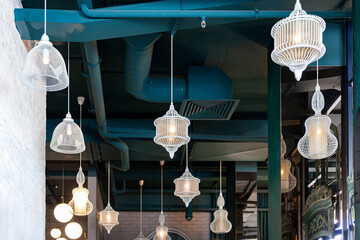 A variety of white wire pendant lights glow in the interior. Ceiling lamps hang from the ceiling. Birdcage lamps