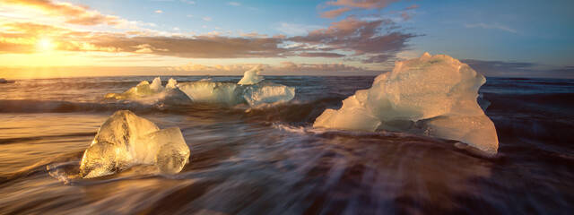 Bright sunshine over icy winter iceberg filled ocean in Iceland with cold sea water and floating glacier  