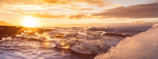 Sunrise over glacier iceberg washed up on black sand beach in Iceland 