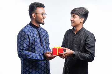 Two handsome men wearing traditional outfit Kurta and holding gift boxes and posing different poses