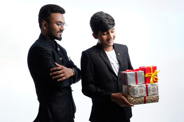 Brothers looking at gift boxes wearing blazers or traditional wear during the festival