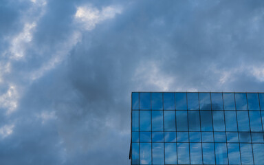 Fototapeta premium Sky reflection on the facade of a new modern glass and steel office corporation building.