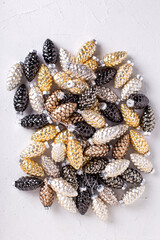 Flat lay with  Christmas decorations. Glass gold, black, silver decorative cones on grey textured background. Scandinavian minimalistic style. Still life. Top view.