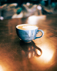 Blue cup of coffee with latte art flower.