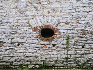 Grunge grey brick wall with a hole. Background with green ivy, copy space, texture pattern.