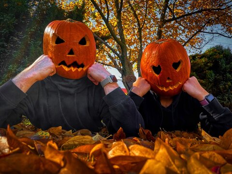 Halloween pumpkin head people with black outfit and pumpkins on head photoshoot. Pumpkin head people photo scary in the forest autumn colourful trees. Pumpkin head with cat. Halloween couple photos.
