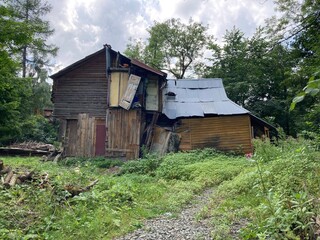 Mountain modern house. Old cabin log house in the mountain. Shelter on the hiking path. Wooden house in the forest in mountains. Old wood and stone house with the trees. Summer hiking day.