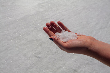 Fototapeta na wymiar A handful of Salt in a woman's hand, salt in the background. High-quality photo