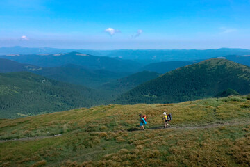 Two hikers with backpacks are walking along mountain range in Carpathian mountains