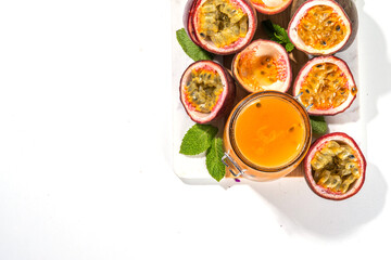 Homemade passion fruit jam in small jar, with fresh passion fruit and mint leaves on white kitchen background copy space