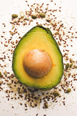 Close-up photo of a cut avocado on a white background sprinkled with grains.