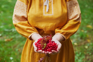 beautiful Ukrainian woman in an embroidered dress holding viburnum