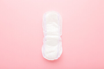 Opened white thick sanitary towel on pink table background. Pastel color. Closeup. Female hygiene product for urinary incontinence or after childbirth. Top down view.