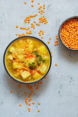 Soup with red lentils and vegetables in a bowl on a blue background.Traditional dish of Turkish or Arabic cuisine, vegan healthy food.