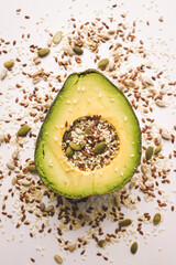 Close-up photo of a cut avocado on a white background sprinkled with grains.