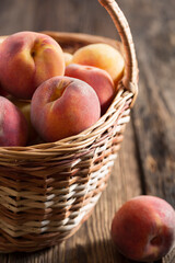 Ripe peaches in a basket on a wooden table, close-up, rustic style