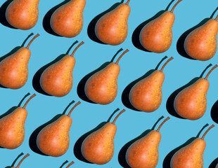 Colorful pear pattern. Yellow and orange Bera pears on a blue background. Ripe juicy fruits top view. Food background. Creative concept.