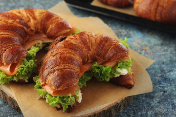 Freshly baked croissants with salmon and salad on the table