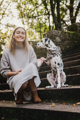 Junge Frau mit jungen Dalmatiner (Junghund / Welpe) während Herbstausflug auf Treppe