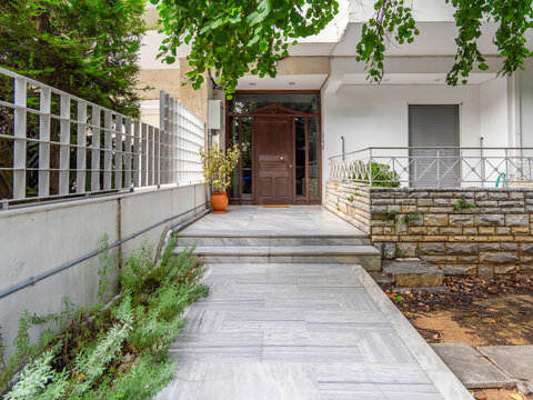 Exterior house entrance with marble floor and wooden door with classic design.