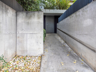 Modern, bare concrete house entrance and walkway to metal security door. Athens, Greece.