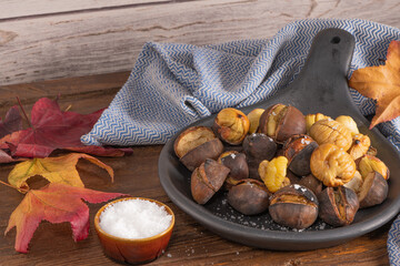 Roasted chestnuts in cast iron pan on an old board