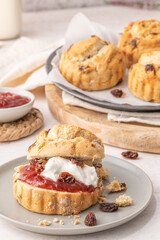 Homemade raisin scones with clotted cream and strawberry jam ready to eat