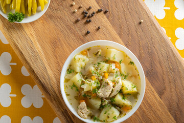 Chicken soup with potatoes and noodles on a wooden rustick cutting board