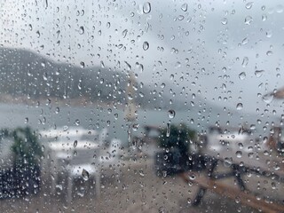 Regen auf Scheibe mit Blick auf Gartenstühle am See 