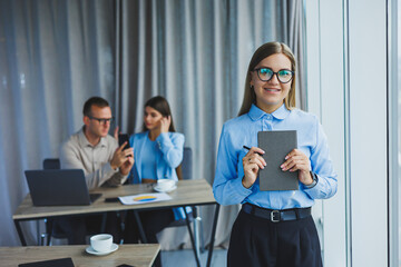 A young woman with a gray notebook in her hands. Notepad for recording cases. Businesswoman makes notes with a pen