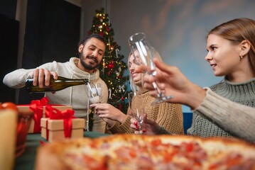 The guy pours champagne to the girl for the celebration of the New Year. A young company pours...