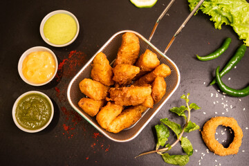 wedges with onion ring and sauces served in a fryer isolated on table top view of fastfood