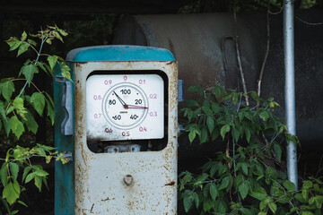 Old rusty abandoned gas station overgrown with grass and trees