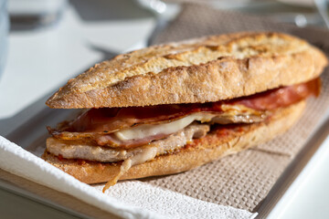 Close-up, sandwich with pork loin, tomato, bacon, cheese and Serrano ham