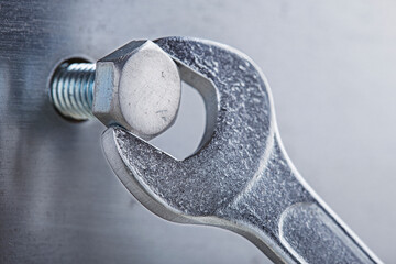 Wrench tightens bolt in steel billet. Spanner, bolt, screw and nuts.