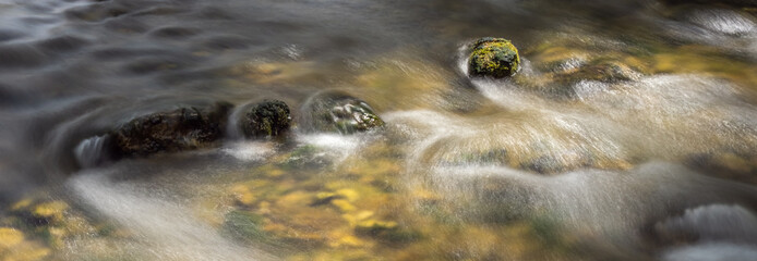 Long exposure with a rock in the colorful riverbed with water flowing 3