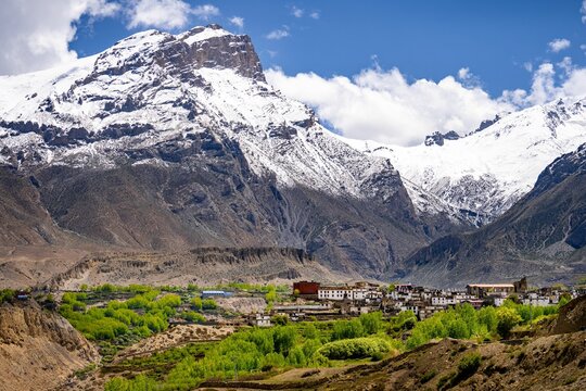 Aerial shot of a town located near high snowy mountains under a blue sky in Upper Mustang, Nepal
