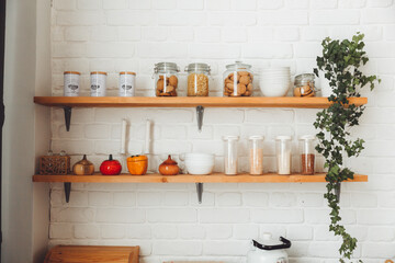 Various cereals in glass jars, placed on wooden shelves in the kitchen. pasta and cereals