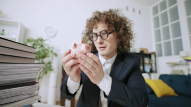 Closeup of funny geeky office worker putting coins in piggy bank, low salary