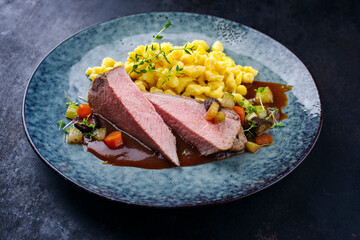 Tafelspitz Braten vom Kalb mit schwäbischen Spätzle and Gemüse serviert mit Dunkelbier Sauce als close-up in einem Nordic Design Teller 