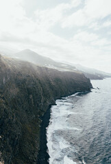 Savage seascape with impressive cliff and rocks. Heavy waves in the beach with black sand