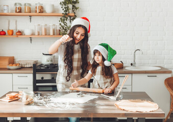 happy cheerful mother and child in Santa Claus hats are cooking Christmas cookies in the kitchen. new year and Christmas