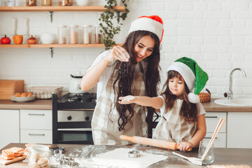 happy cheerful mother and child in Santa Claus hats are cooking Christmas cookies in the kitchen. new year and Christmas